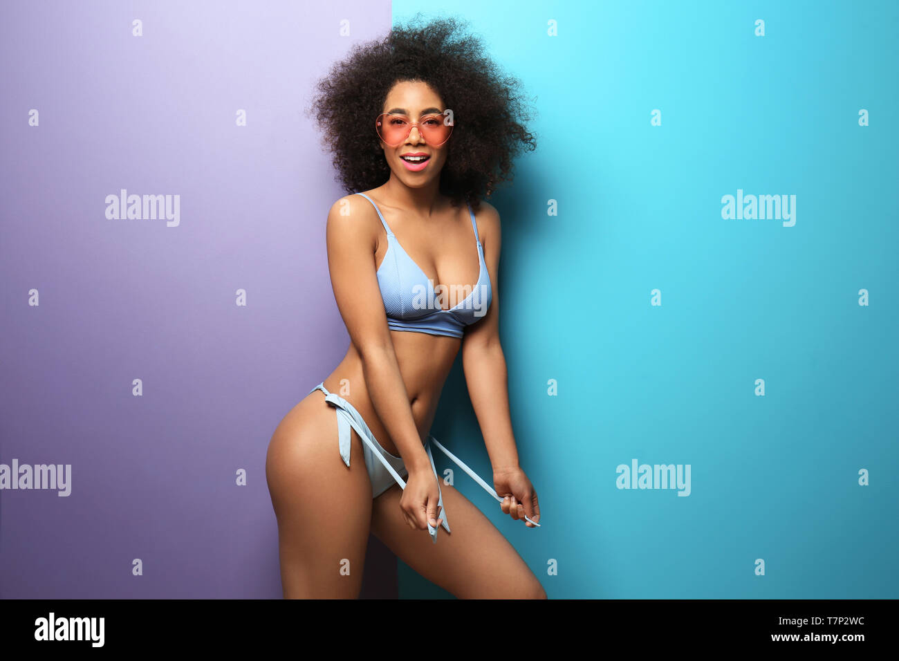 Beautiful African-American woman in bikini and with sunglasses on color  background Stock Photo - Alamy