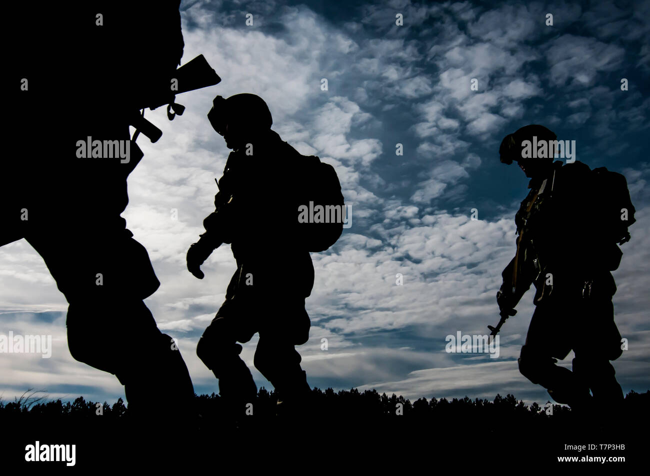 Group of Russian armed Forces Airborne troops (VDV - Vozdushno-desantnye voyska) soldiers marching at exercise silhouette against Sun, sky and clouds Stock Photo