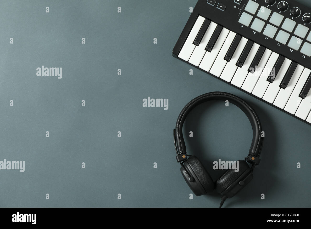 Midi keyboard with headphones on dark background, space for text Stock