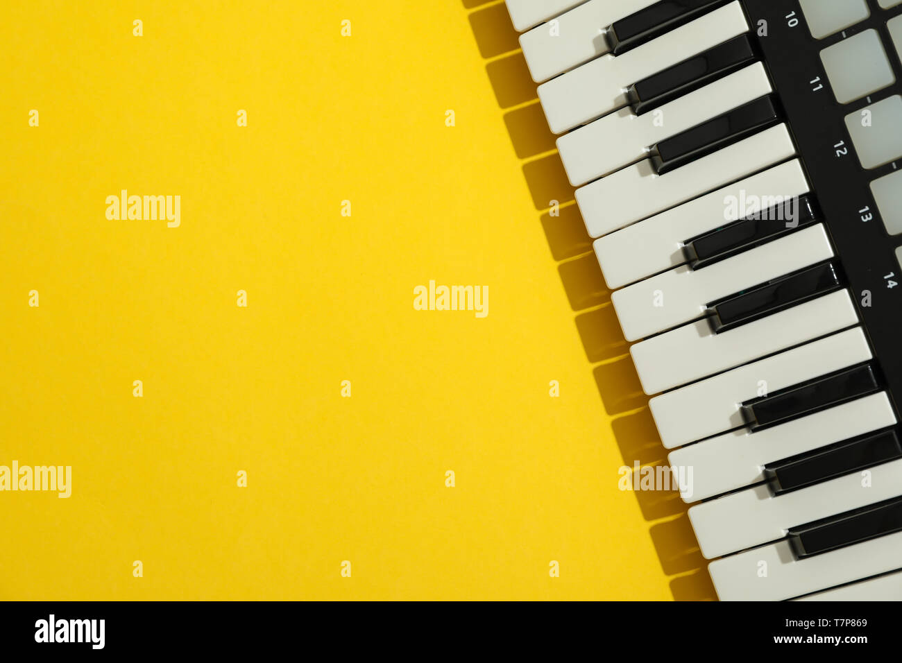 Small MIDI Controller Piano on Yellow Background with Cell Phone