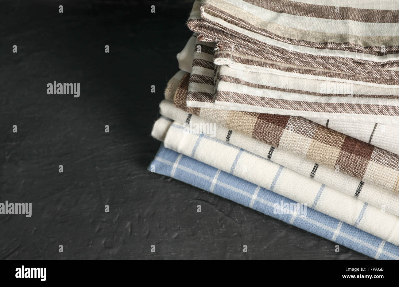 Stack of fabric napkins on black table, space for text Stock Photo
