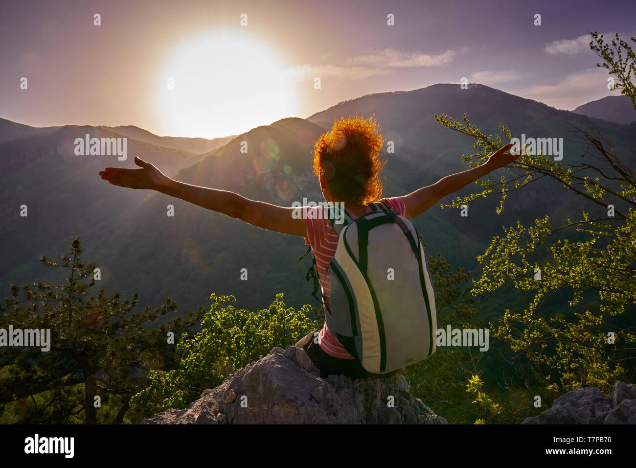 Woman with backpack reaching the top of the mountain at sunset Stock ...