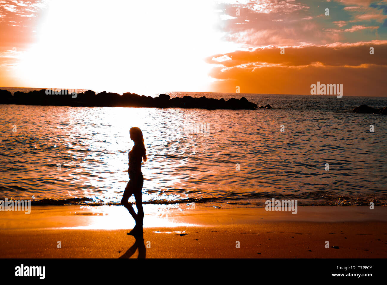 A woman is walking by sunset at the Abama beach on Tenerife south, Canary Islands. A feeling of peace, relax and good vibrations. Stock Photo
