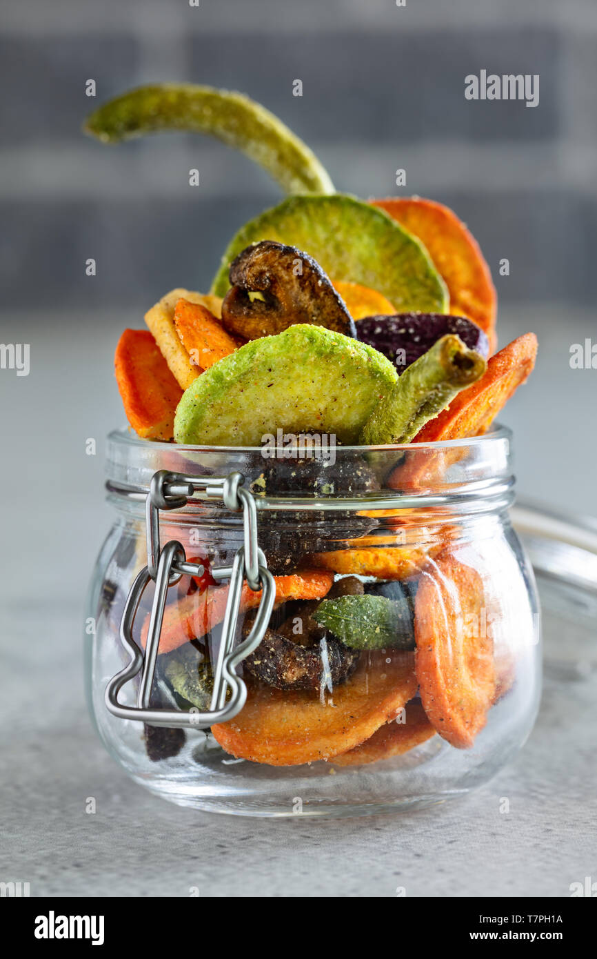 Colourful mix vegetable chips in glass jar, vertical composition Stock Photo