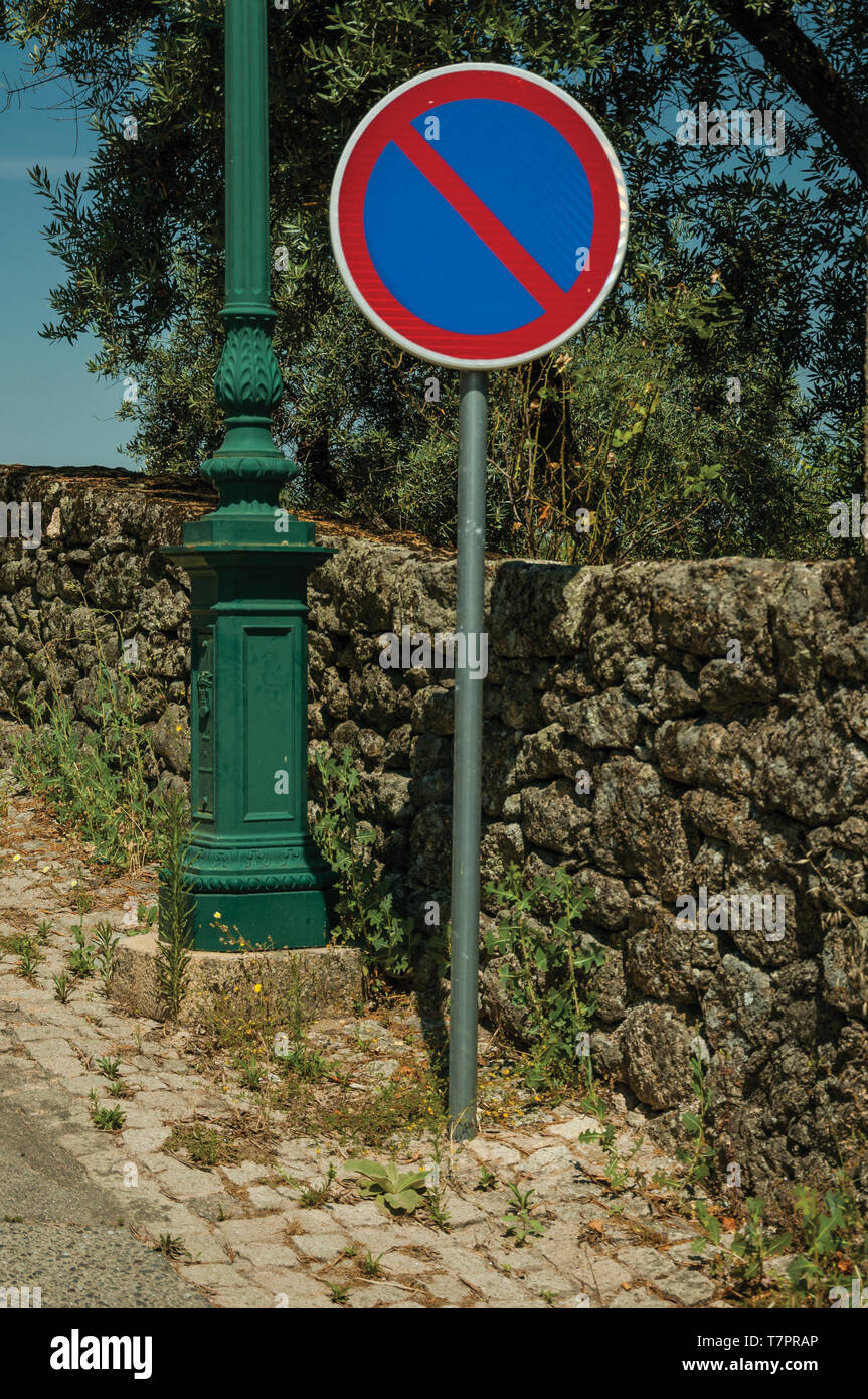 NO PARKING traffic sign post in a sunny day, on cobblestone sidewalk at