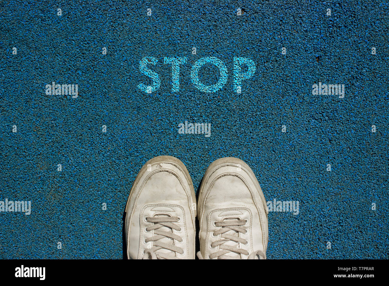 New life concept, Sport shoes and the word STOP written on blue walk way ground, Motivational slogan. Stock Photo