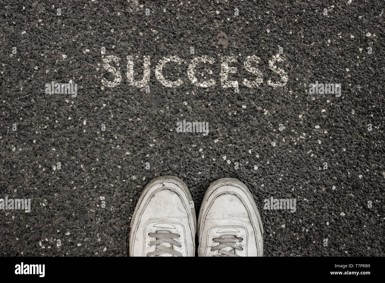 New life concept, Sport shoes and the word SUCCESS written on asphalt ground, Motivational slogan. Stock Photo