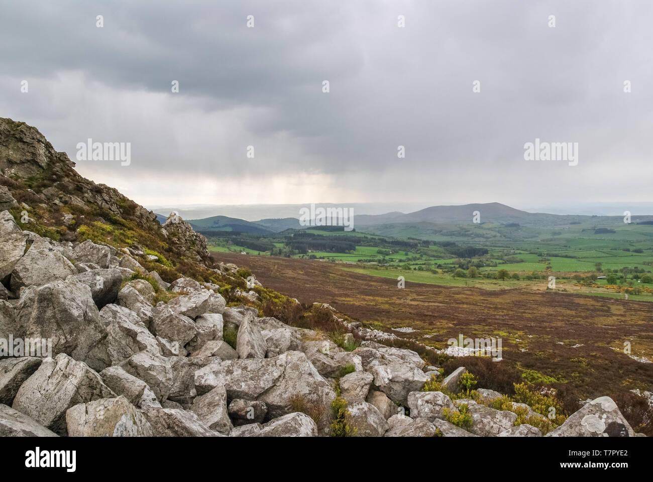 A view of tumbled rocks and stormy skies over distant landscape at Stiperstones Nature Reserve, Shropshire, UK Stock Photo