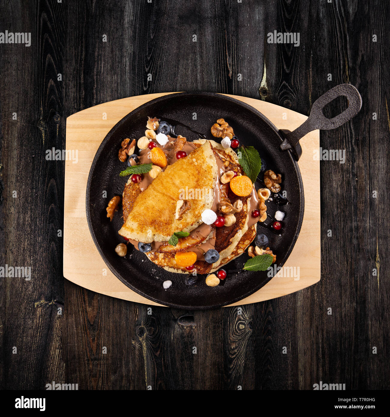 Delicious sweet pancakes served on a cooking pan with fresh fruits, nuts and chocolate sauce Stock Photo