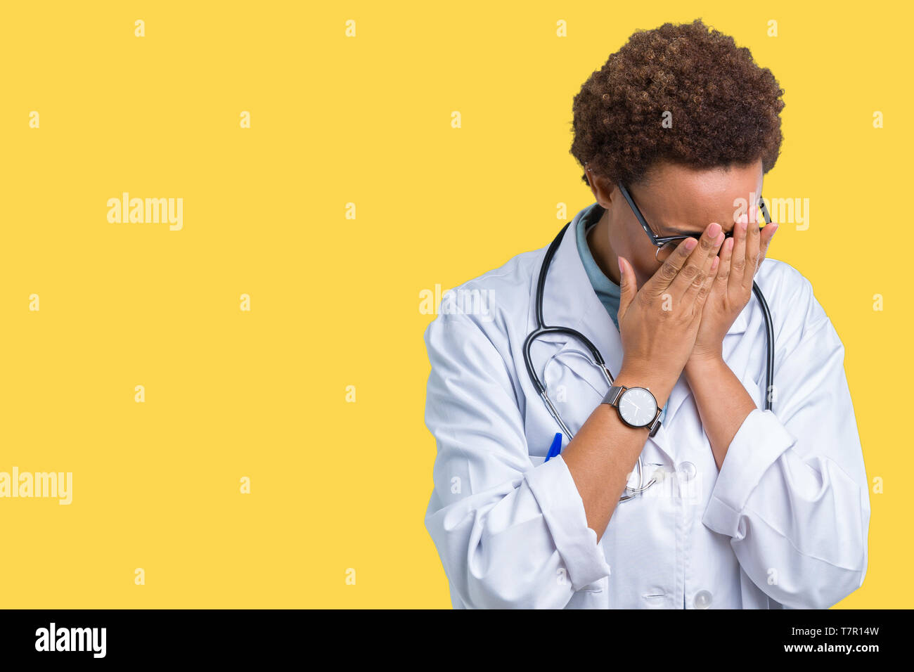 Young african american doctor woman wearing medical coat over isolated background with sad expression covering face with hands while crying. Depressio Stock Photo