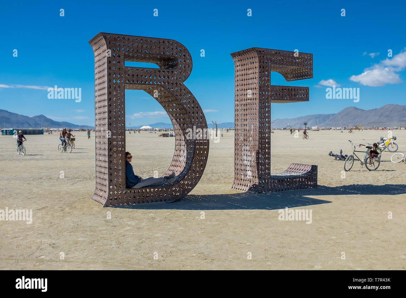 Burning Man, Nevada, USA, September, 6, 2015: Attendees at Burning Man festival standing on and around an artwork of letters that spell out the word, BE against a bright blue sky Stock Photo