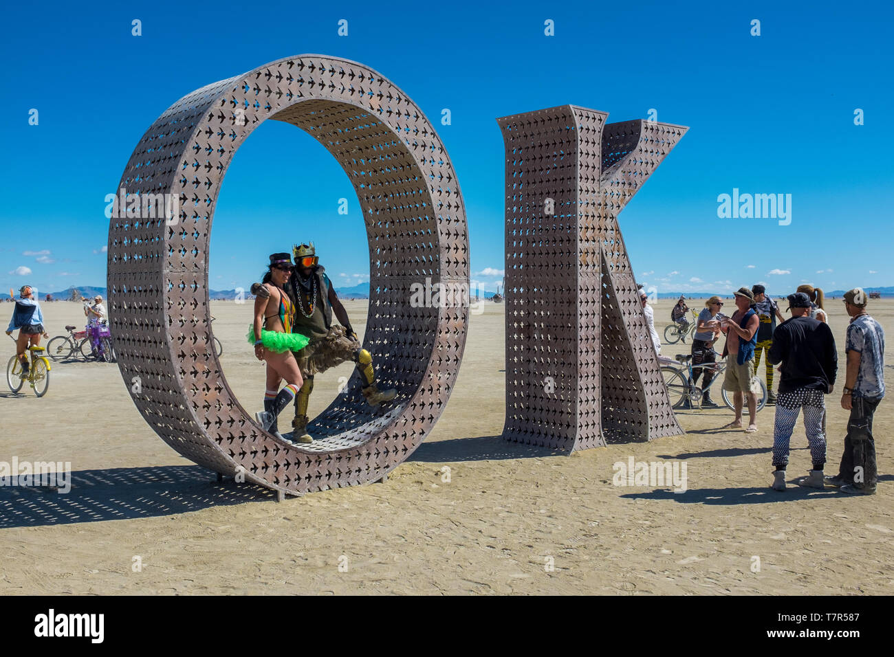 Burning Man, Nevada, USA, September, 6, 2015: Attendees at Burning Man festival standing on and around an artwork of letters that spell out the word, OK against a bright blue sky Stock Photo