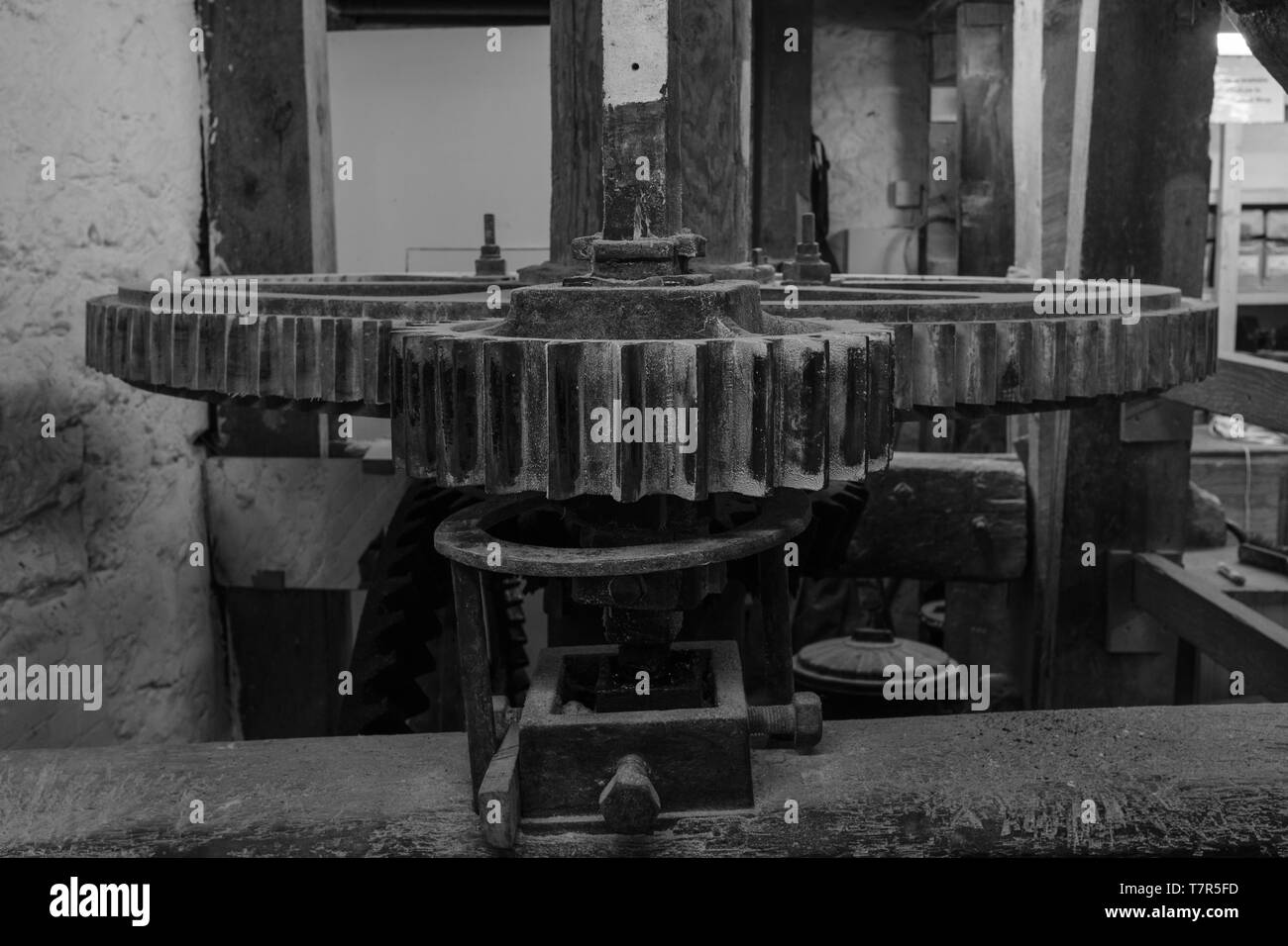 A black and white image of the cogs and machinery inside a watermill in Devon, England, taken from head on of the cogs Stock Photo
