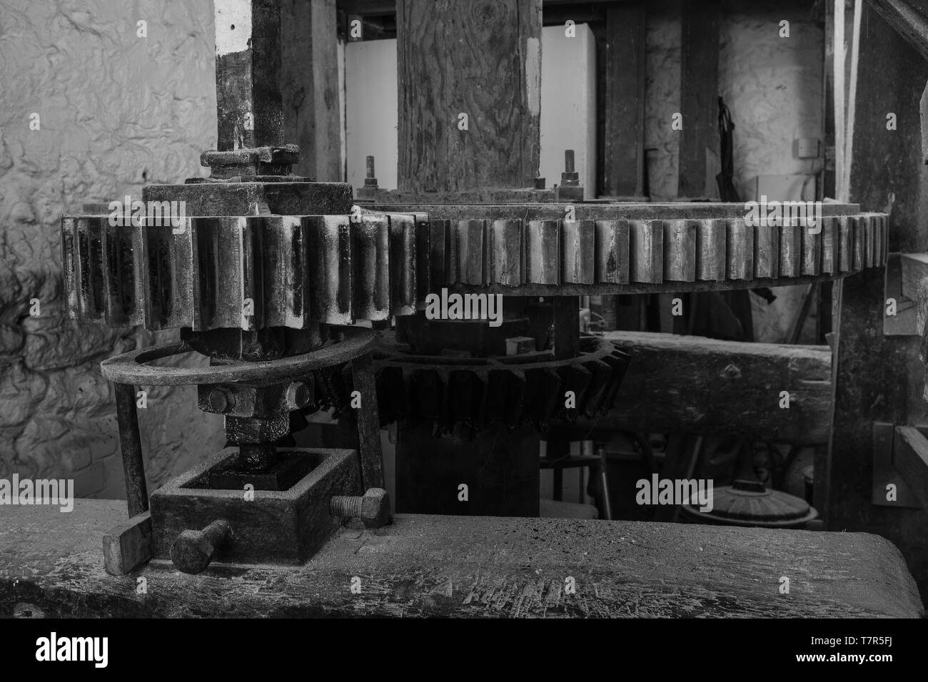 A black and white image of the cogs and machinery inside a watermill in Devon, England, taken from the right of the cogs Stock Photo
