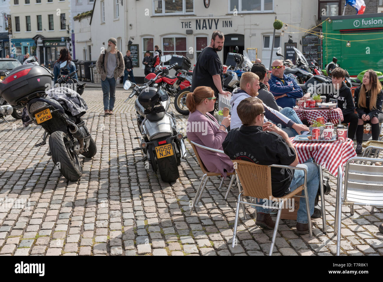Plymouth, Devon, England, UK. May 2019.  Bikers seated with their machines close by on the Barbican waterfront a popular meeting place for riders Stock Photo