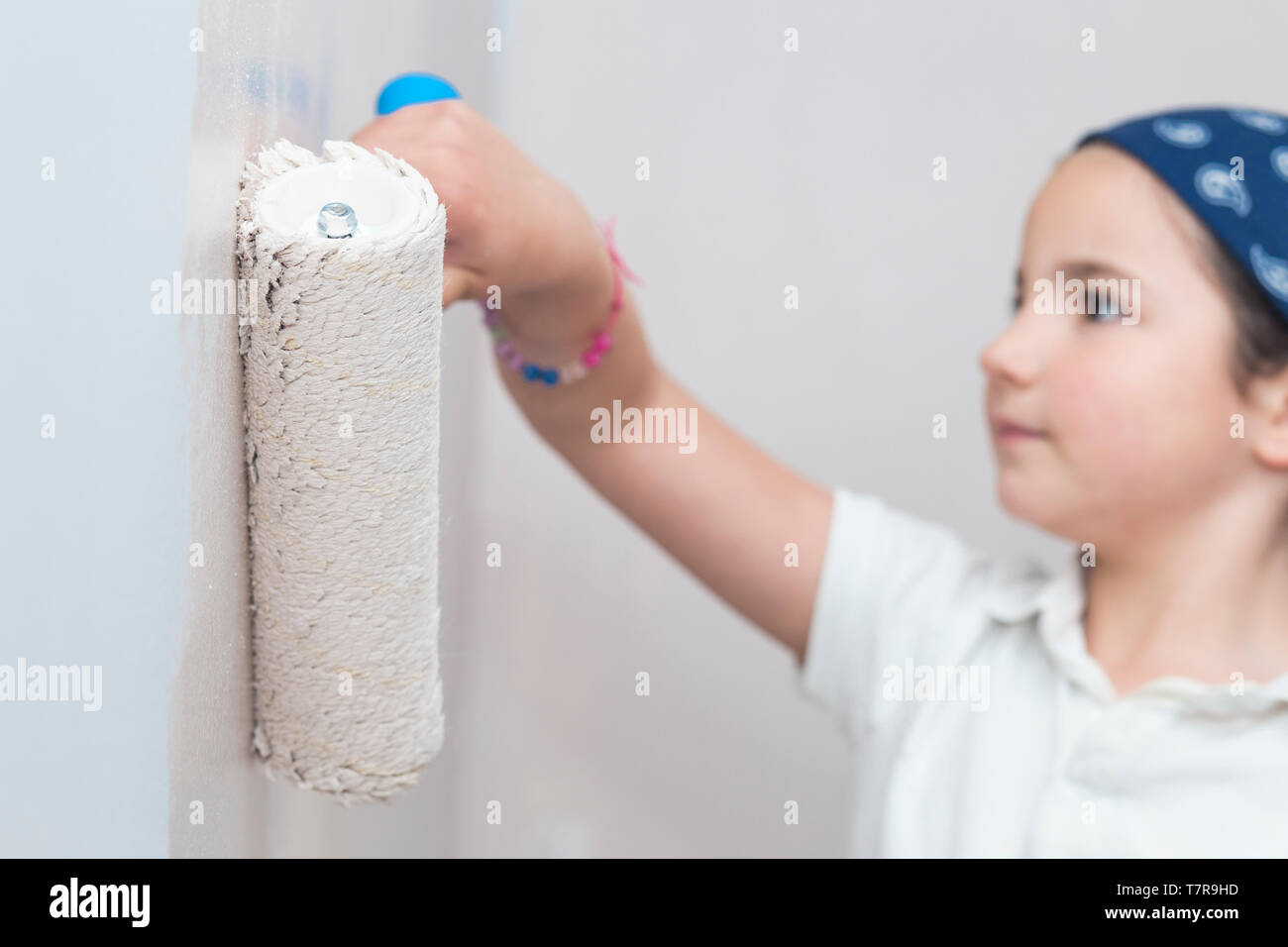 Little girl with paint roller in hand. Kids Helping House Chores concept Stock Photo