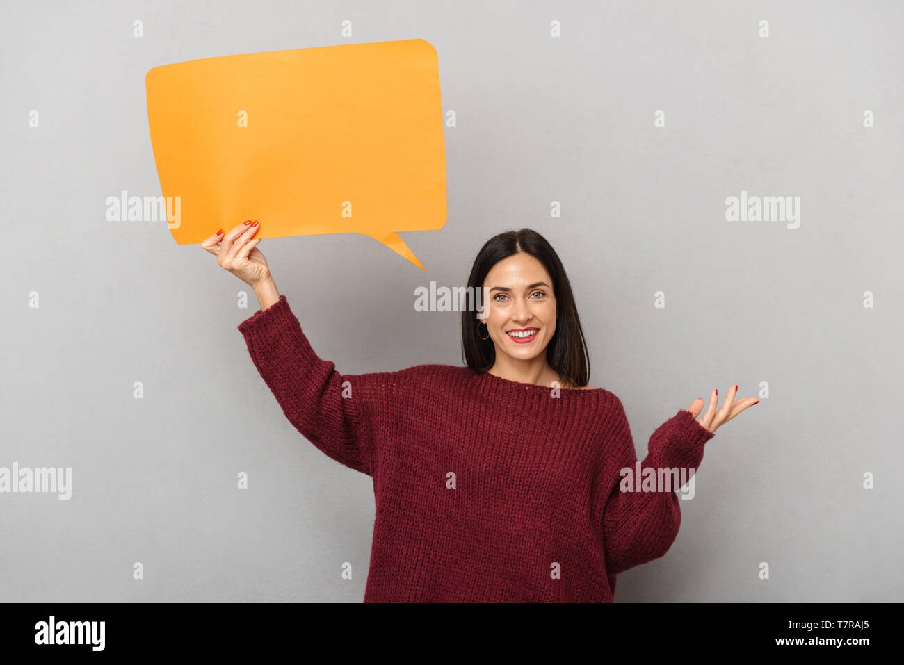 Portrait of joyful woman 30s holding blank placard for text isolated over gray background Stock Photo