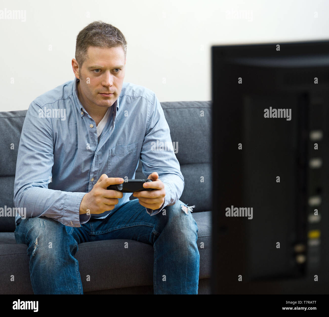 Handsome man playing video game at home. Stock Photo