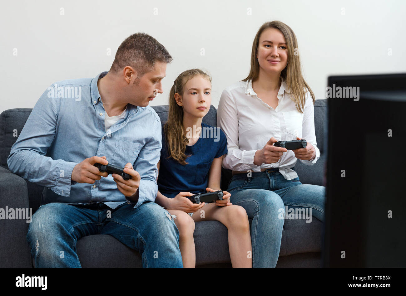 Mom, Dad and their daughter playing video game at home Stock Photo - Alamy
