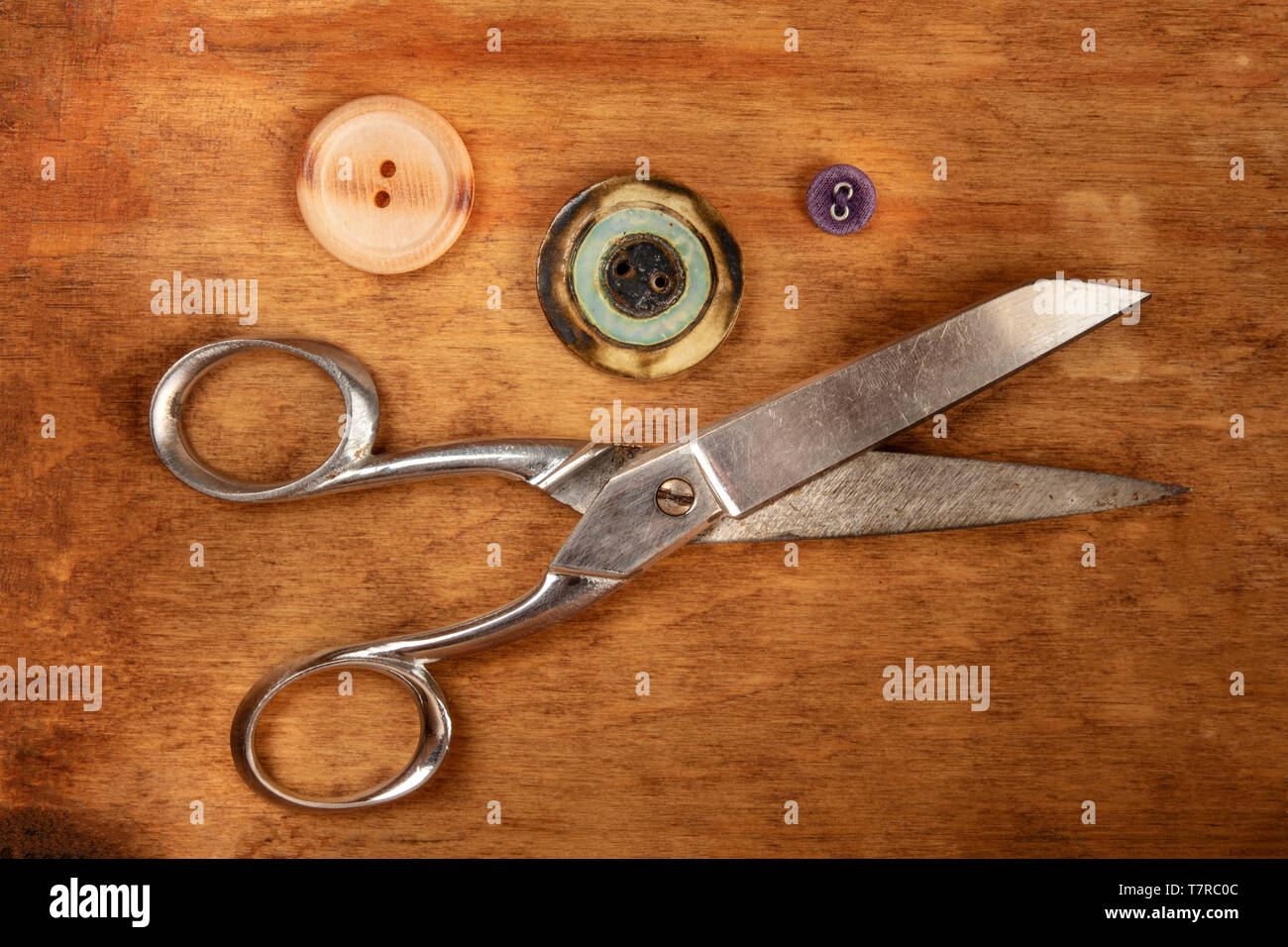 Vintage scissors and buttons, shot from above on a dark rustic wooden ...