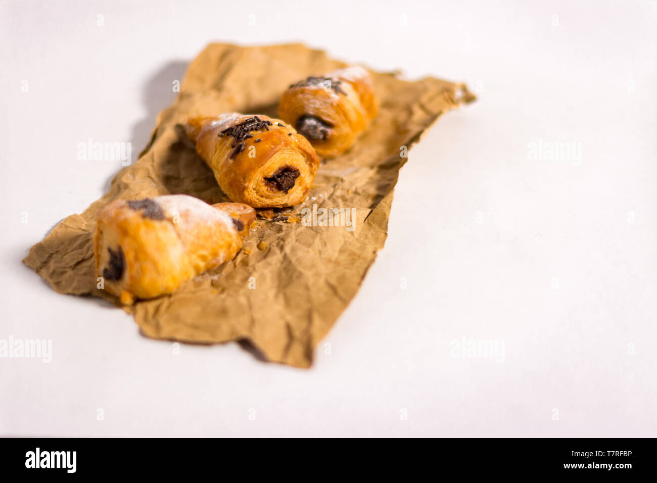 Croissants filled with chocolate on a paper. Isolated with white background Stock Photo