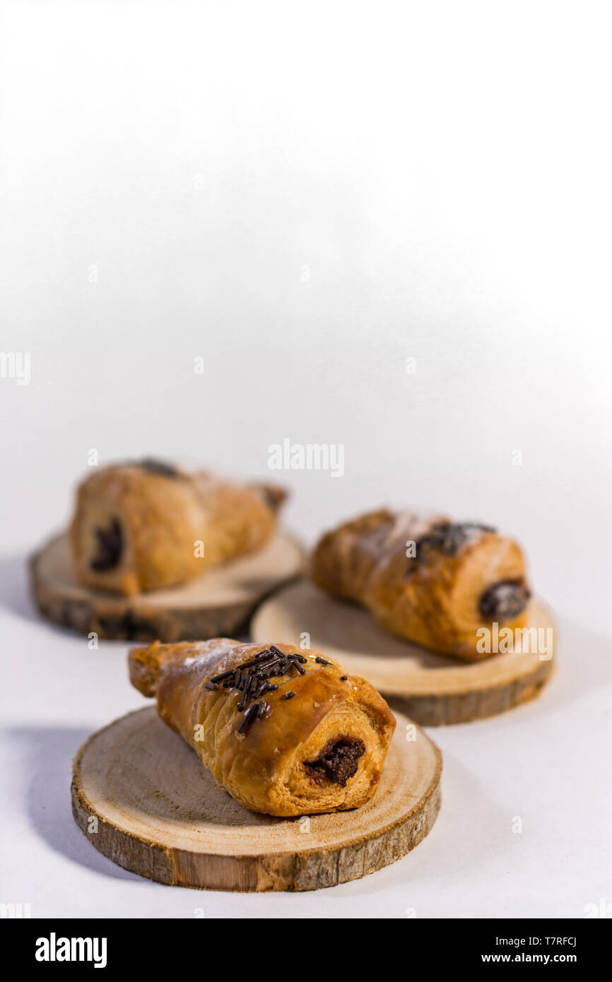 Croissants filled with chocolate on three wood planks. Isolated with white background Stock Photo