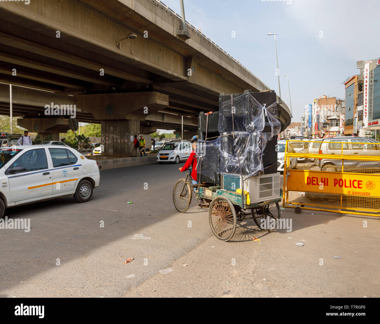 Street scene in Mahipalpur district, a suburb near Delhi Airport in New Delhi, capital city of India: typical overloaded delivery on an old tricycle Stock Photo