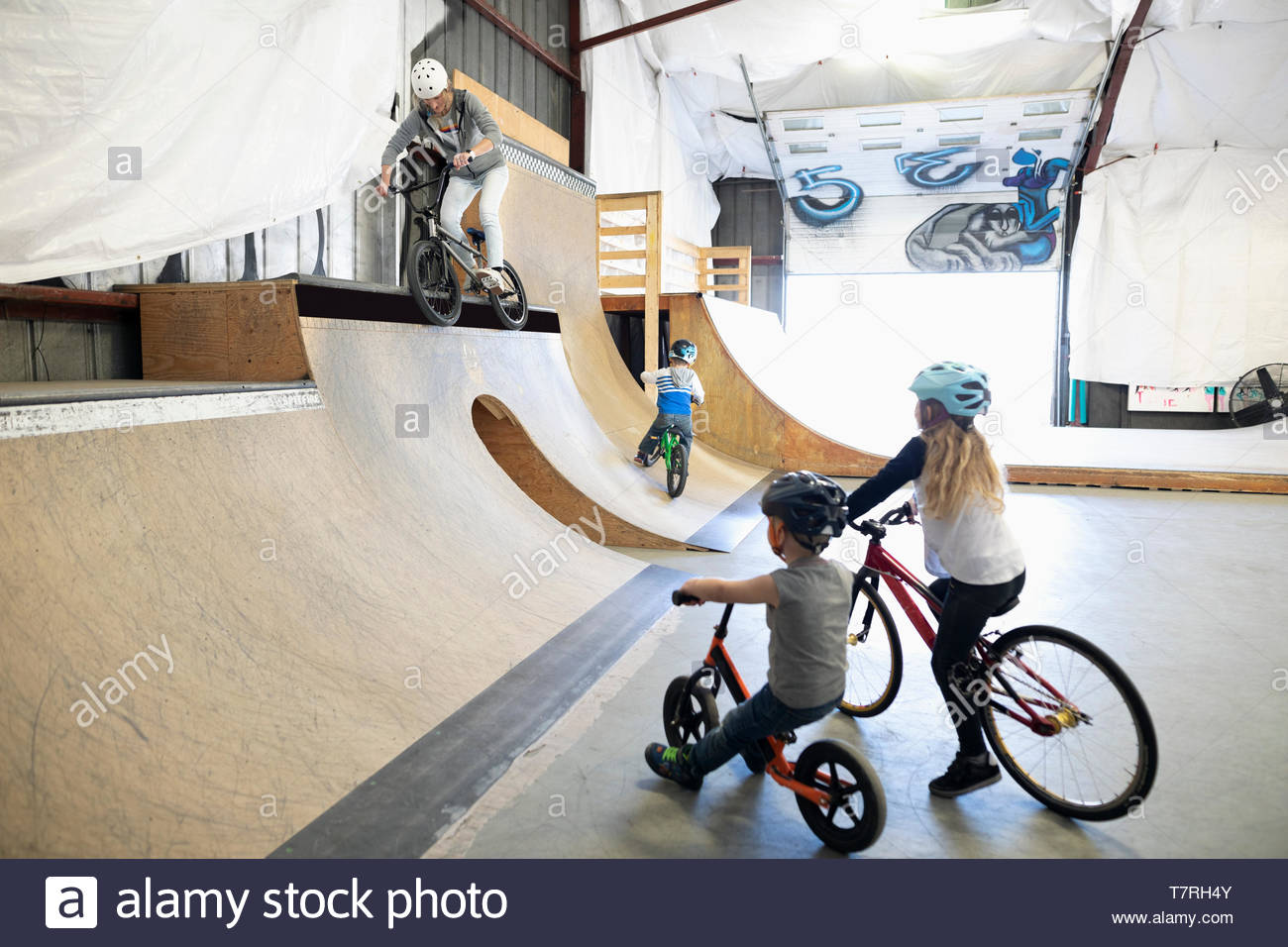 Family riding bmx bikes at indoor skate park Stock Photo Alamy