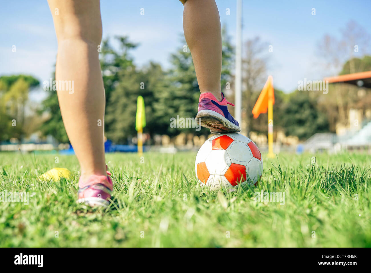 Young female soccer player traning with ball in the stadium - Sporty woman making exercises on the train field Stock Photo