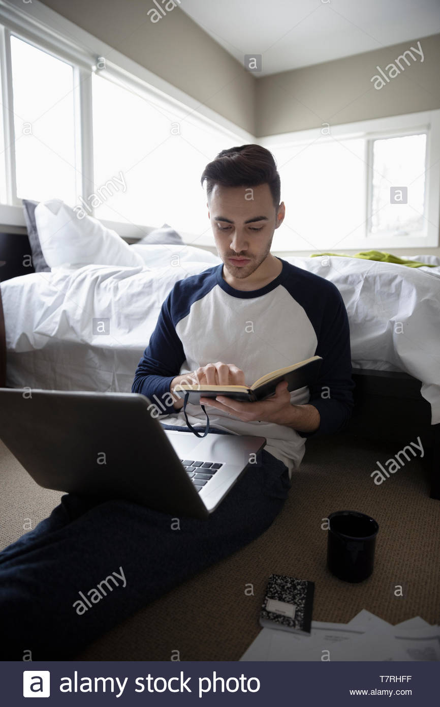 Young man working at home, using laptop in bedroom Stock Photo