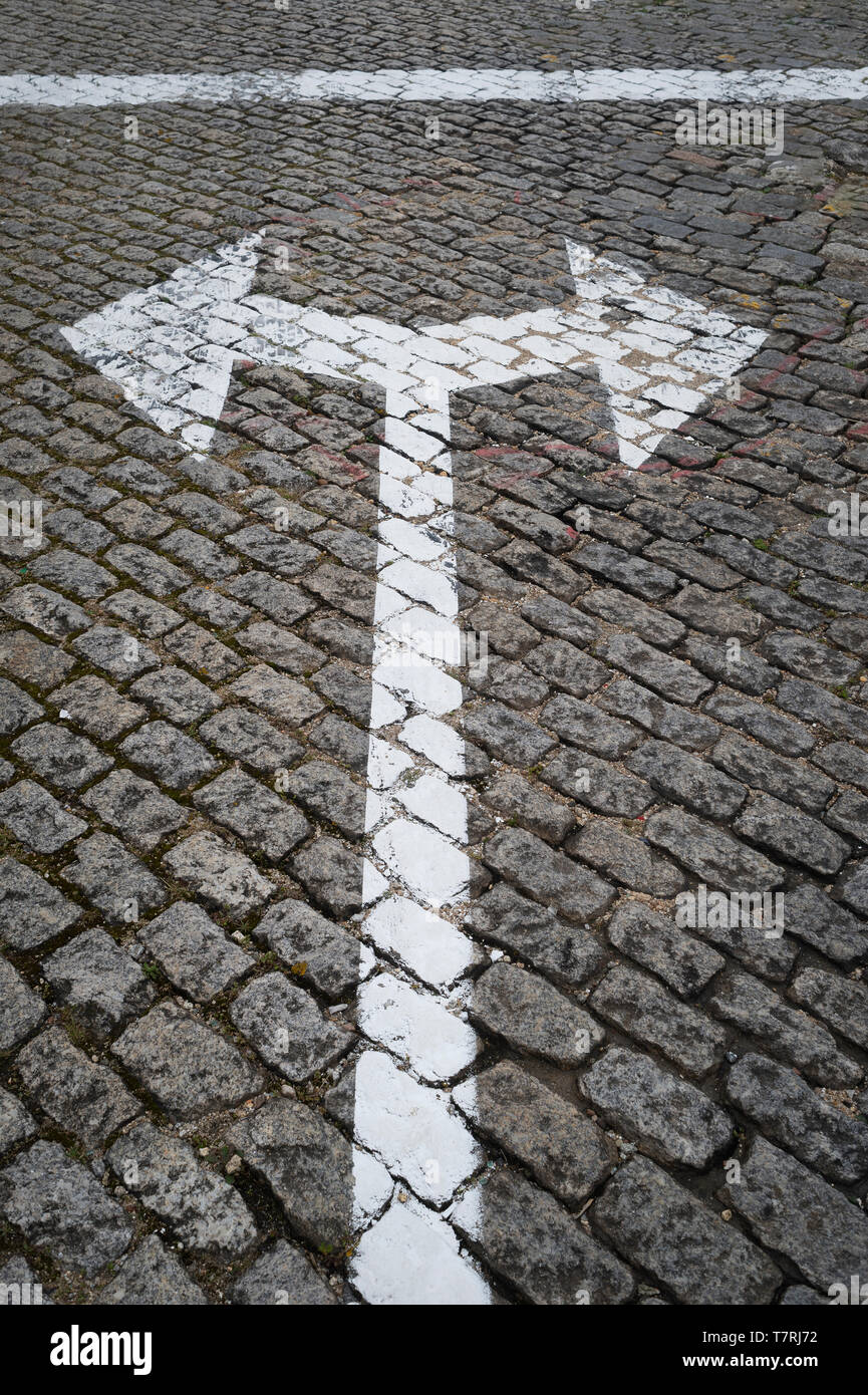 a painted arrow on a cobblestone road with left and right directions, concept. Stock Photo