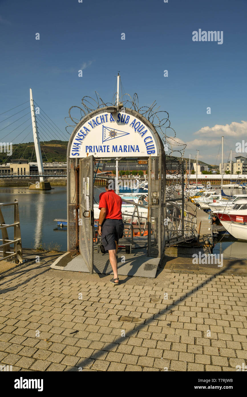 SWANSEA, WALES - JULY 2018: Person opening the security gate to go on to a jetty in Swansea marina Stock Photo