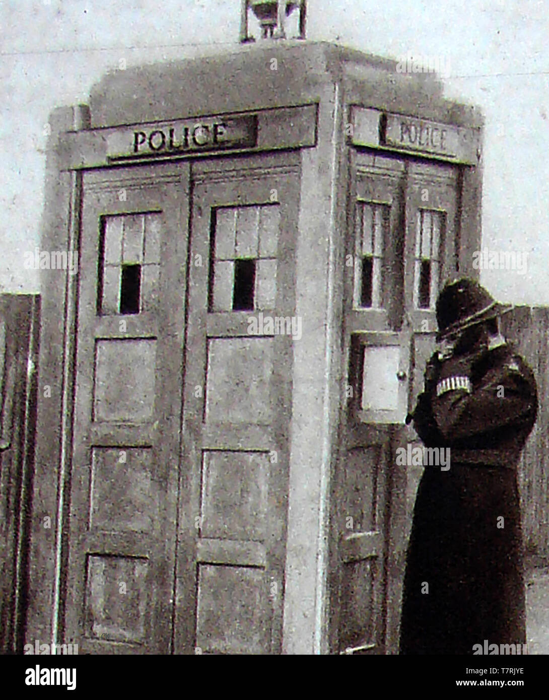 An early Police Box (police telephone box) at Richmond, Surrey, England with a Bobby answering the phone - They were used  by members of the police, or for members of the public to contact the police using the outside accessed phone - Inside the kiosk was a miniature police station containing an incident book, fire extinguisher and first aid kit Stock Photo