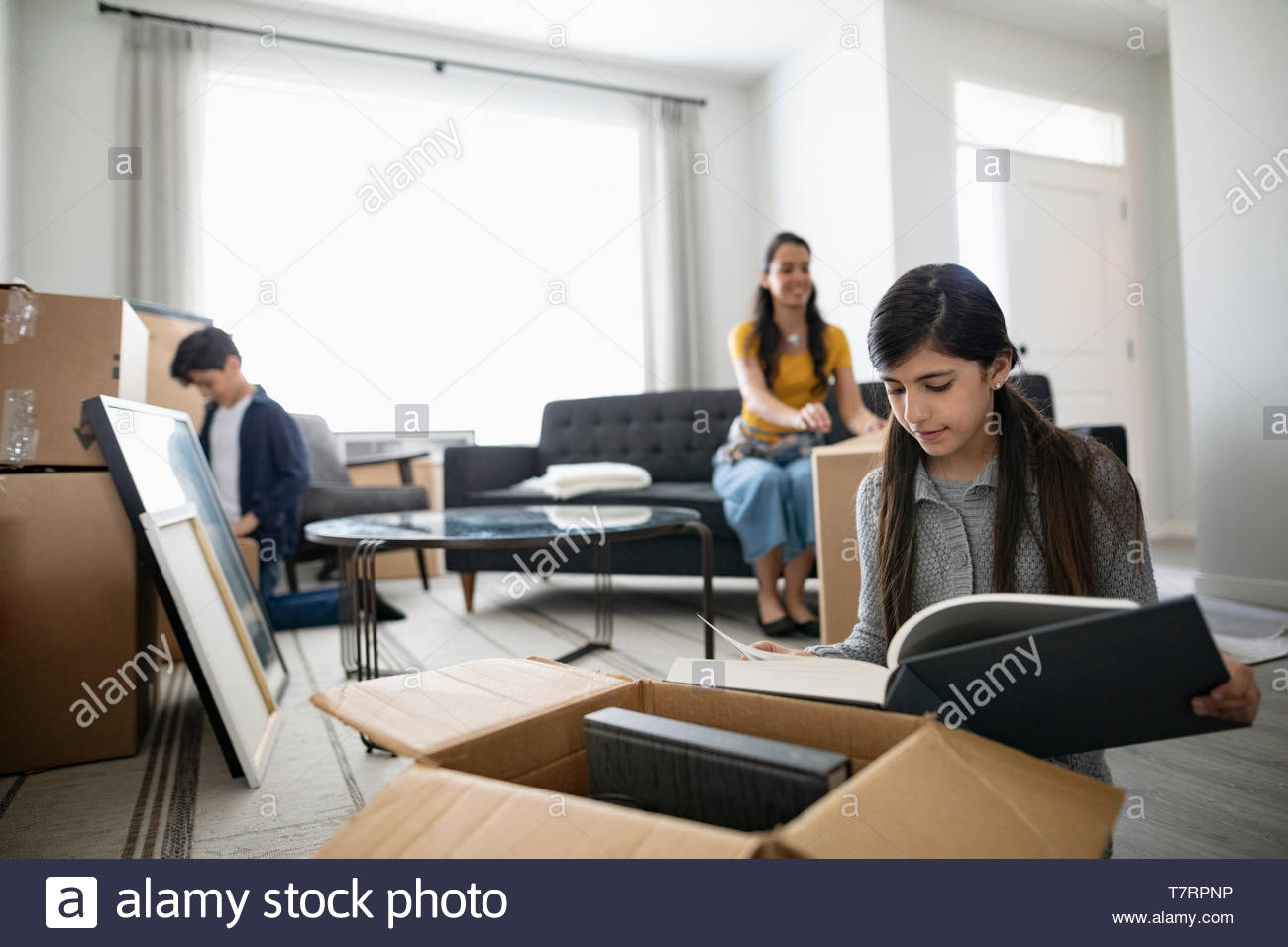 Girl unpacking moving boxes, looking at photograph album Stock Photo