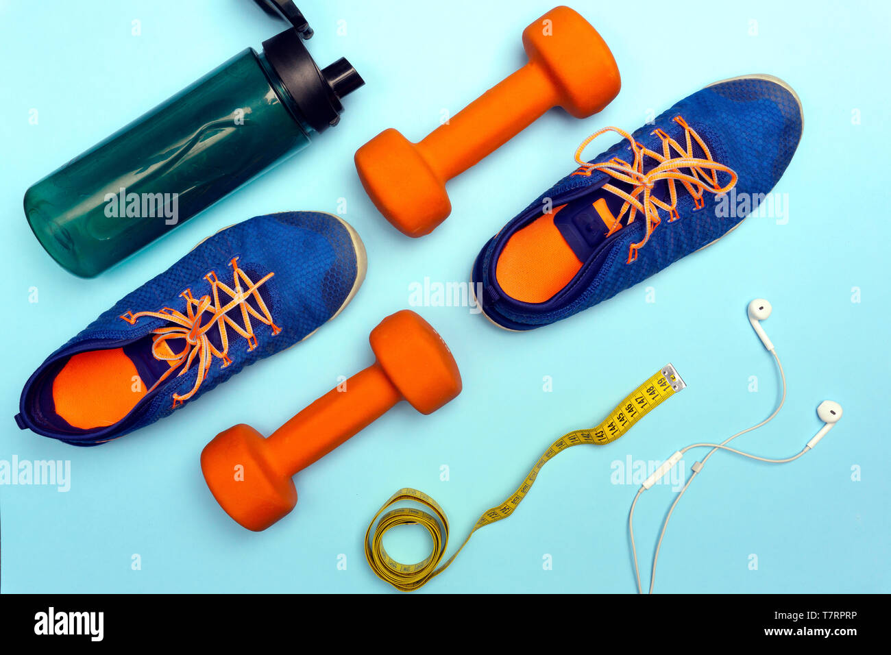 Sport concept with sport equipment composition. Sneakers, dumbbells, bottle of water on bright blue background. Weight loss, flat lay Stock Photo
