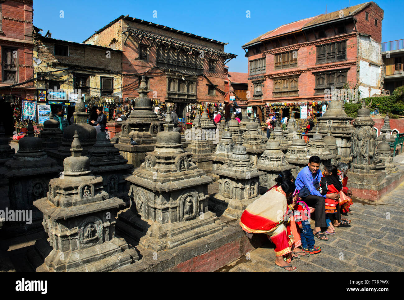 Local family in colorful dresses resting on a square with stupas on the site of the Swayambhunath temple or Monkey Temple, Kathmandu, Nepal Stock Photo