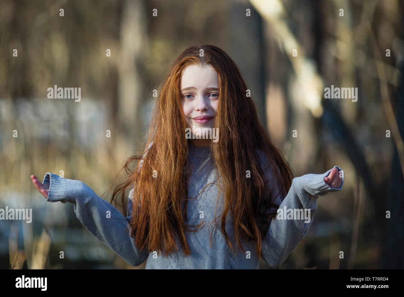 Cute teengirl with fiery red hair in the pine park. The girl was