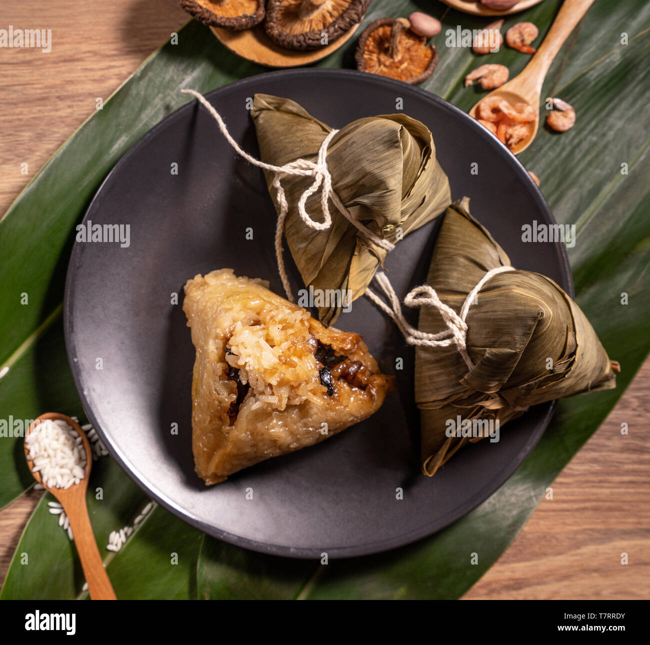 Zongzi, steamed rice dumplings on wooden table bamboo leaves, food in dragon boat festival duanwu concept, close up, copy space, top view, flat lay Stock Photo