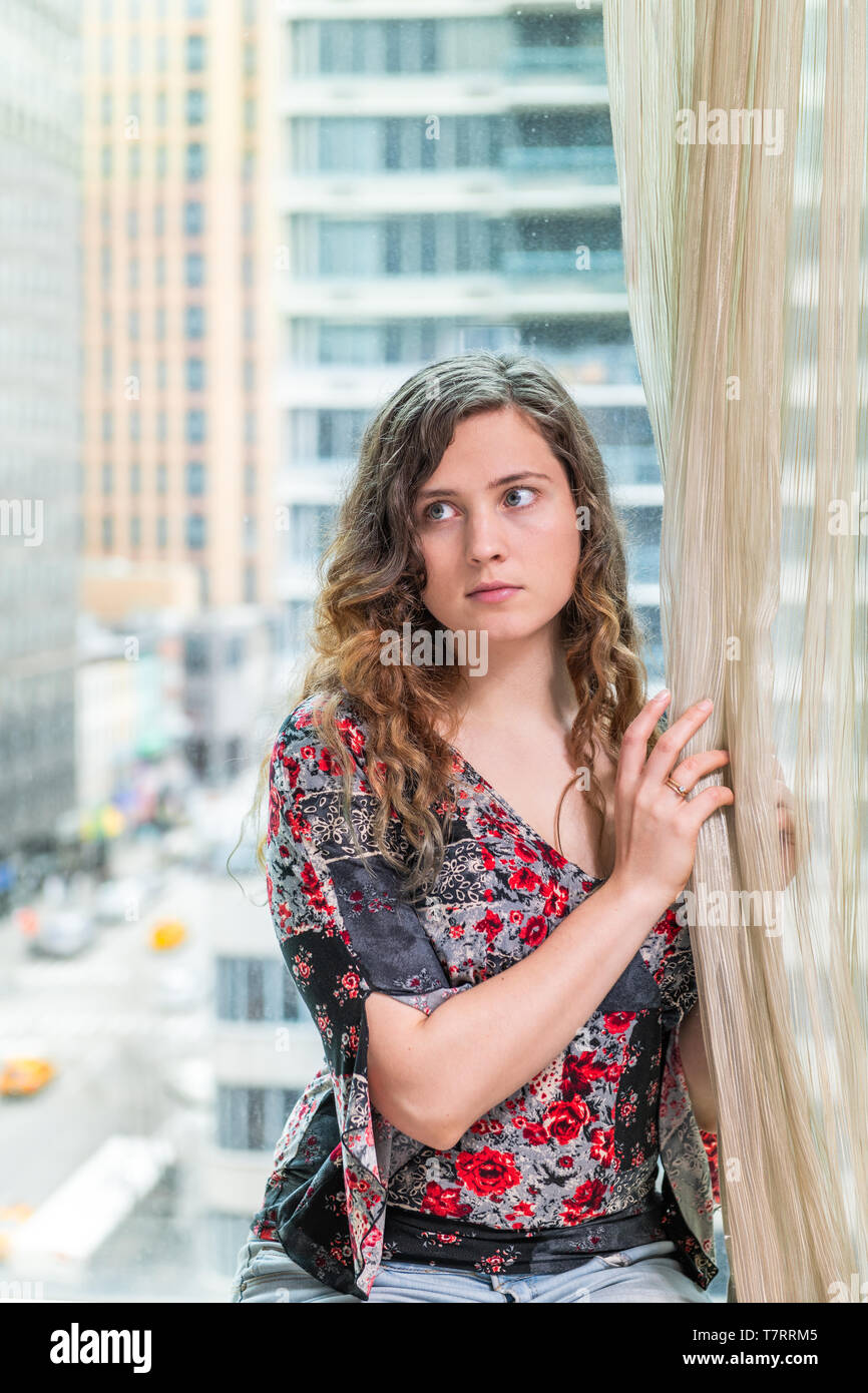 Office buildings glass window of young woman girl sitting face portrait looking sad scared by corporate view dreaming in midtown in NYC Stock Photo