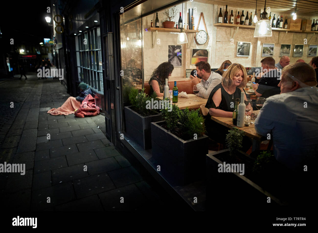 Iconic Newcastle upon Tyne homeless man sleeping on the street as the a full restaurant part on