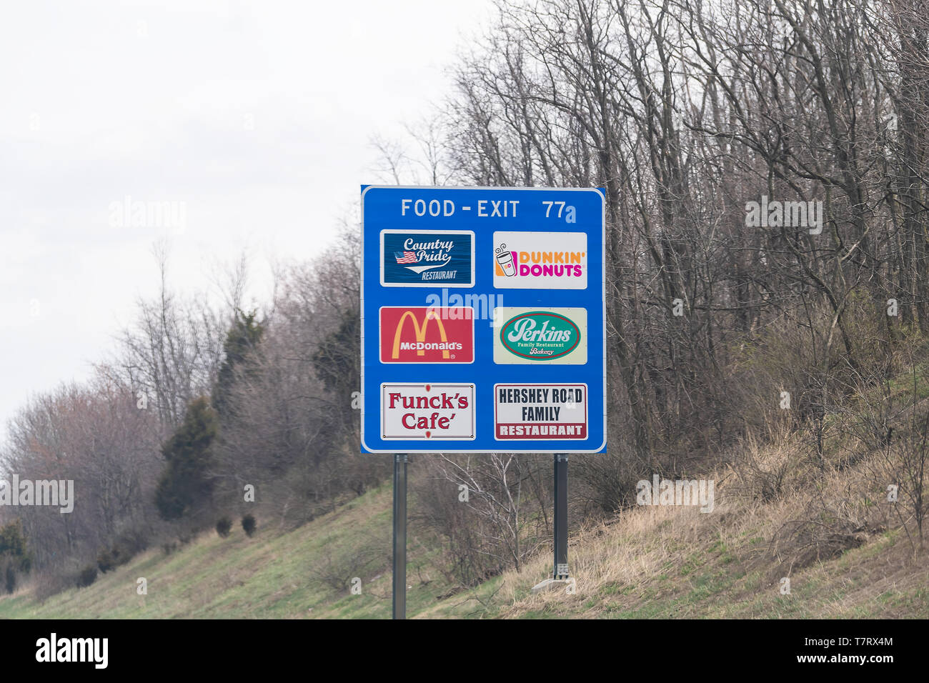 Harrisburg, USA - April 6, 2018: Rural Pennsylvania countryside in spring with blue exit sign on highway for food with Dunkin Donuts, Mcdonalds Stock Photo