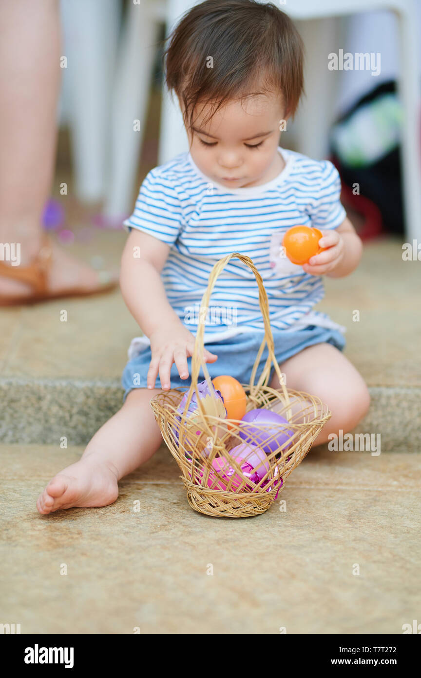 Baby play with eggs in basket during easter hunt Stock Photo