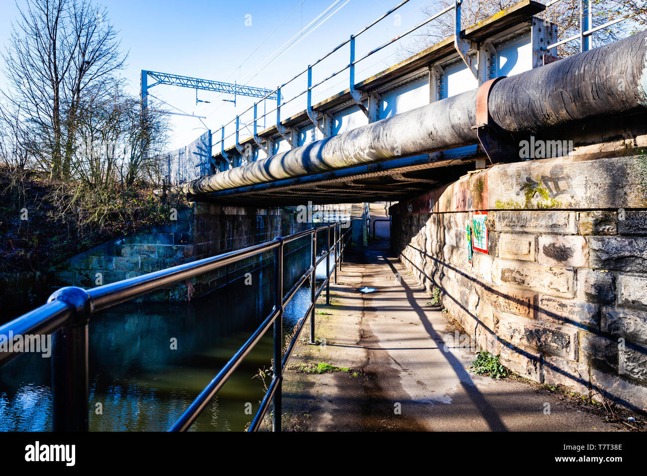 Towpath under a large pipe, and railway bridge. Stock Photo