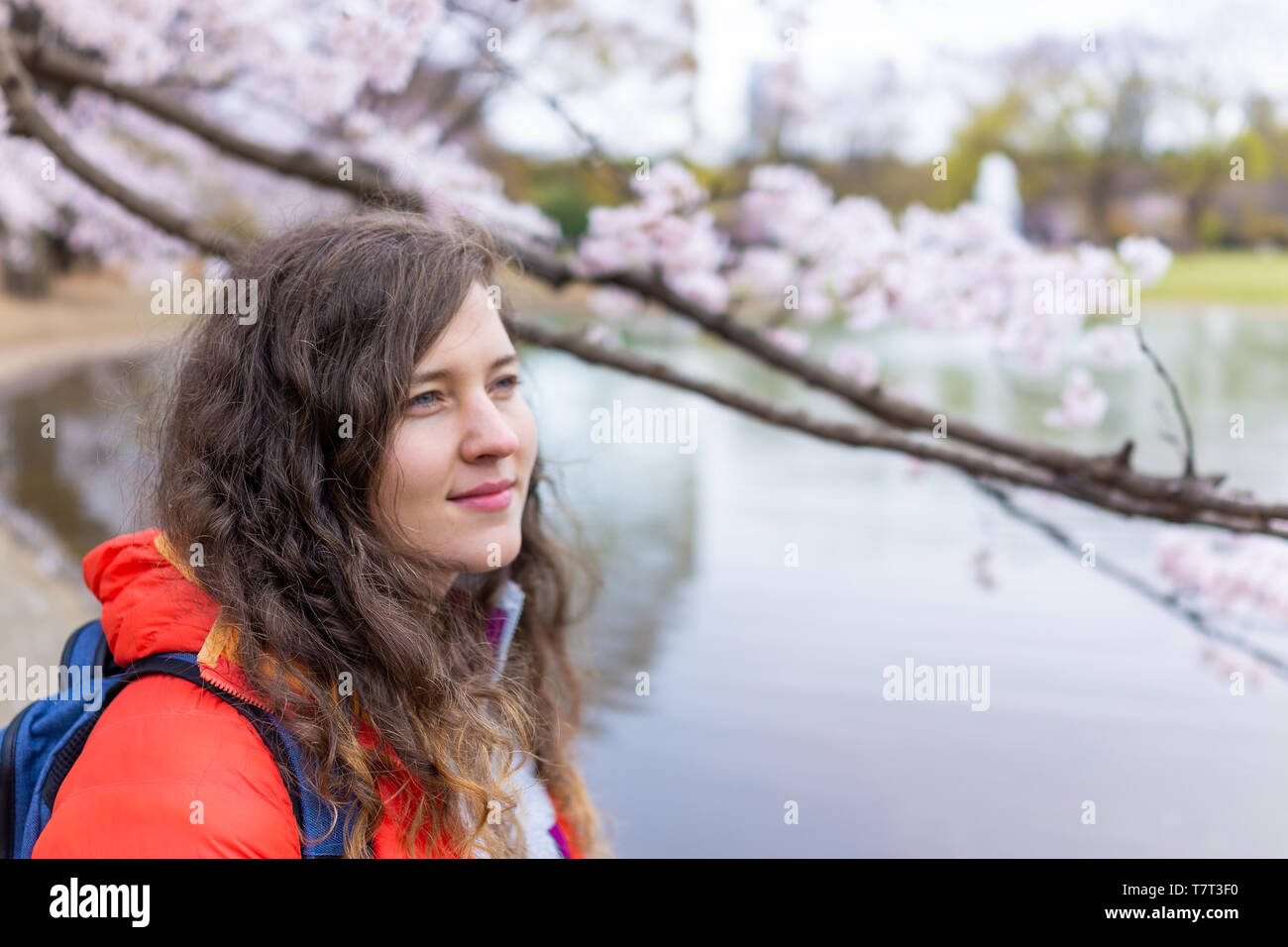 Tokyo, Japan Yoyogi park with young tourist woman standing looking at cherry blossom in downtown on cloudy day by lake Stock Photo