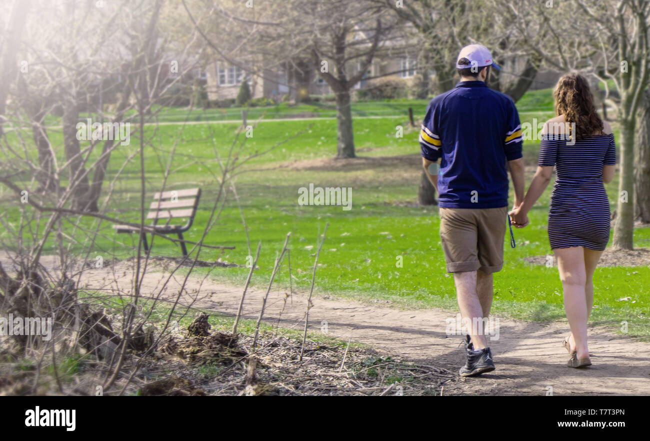 A young couple walks thru the park in Stratford. View from behind. Stock Photo