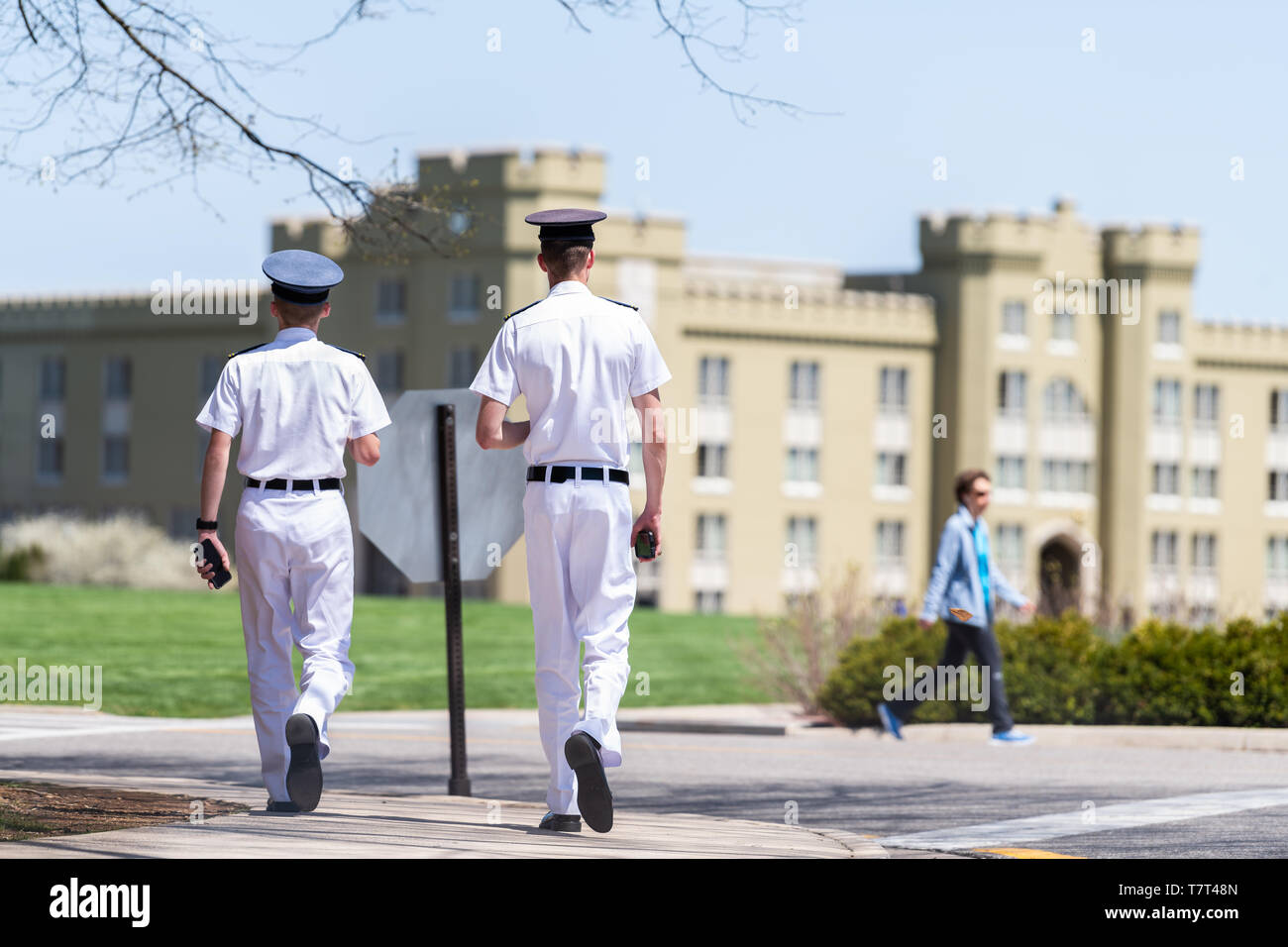 Lexington, USA - April 18, 2018: Men, male cadets students in white uniforms with phones walking at Virginia Military Institute main campus grounds in Stock Photo