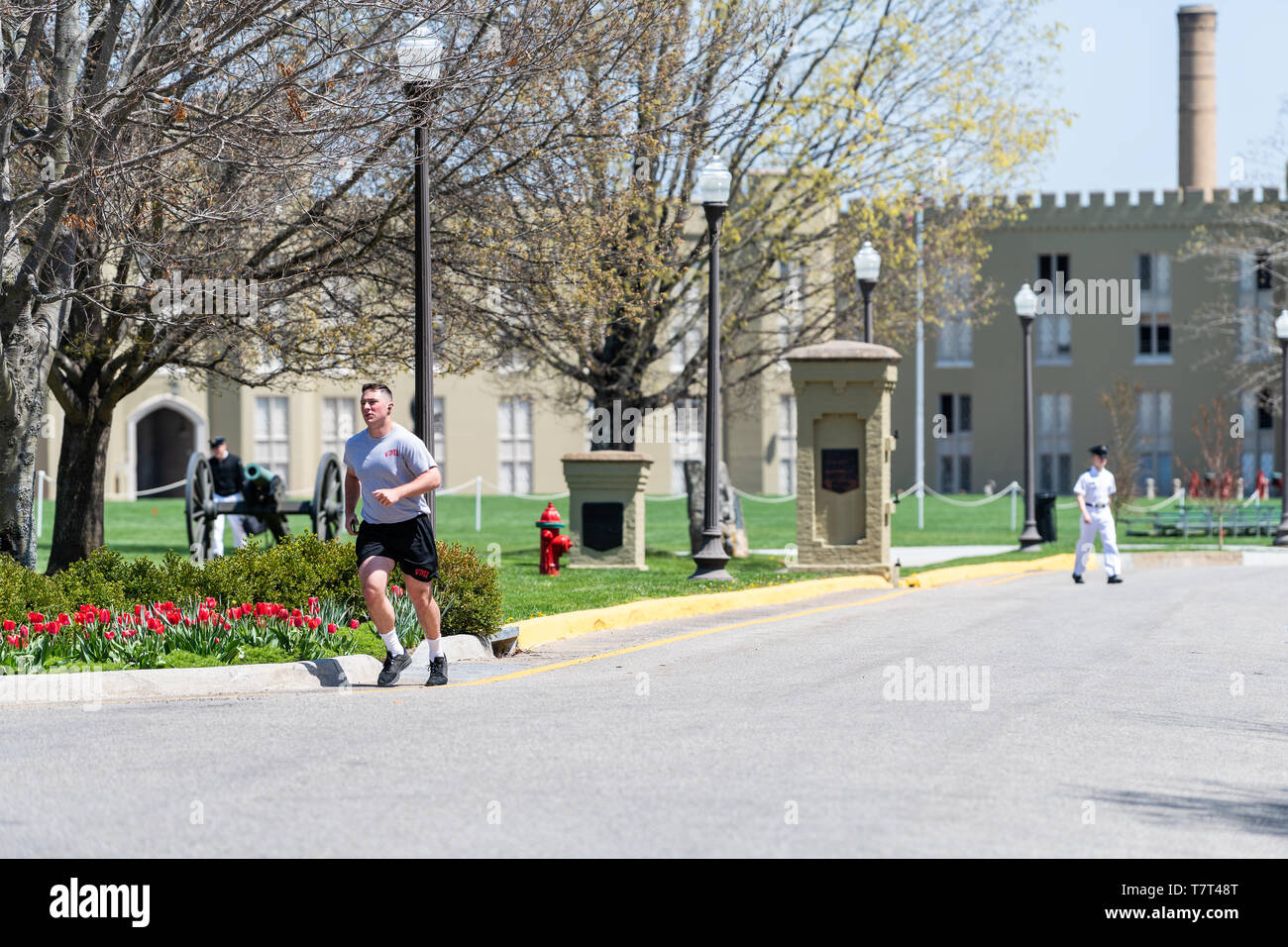 Lexington, USA - April 18, 2018: Man training, jogging or running at Virginia Military Institute main campus grounds with cadets walking in white unif Stock Photo