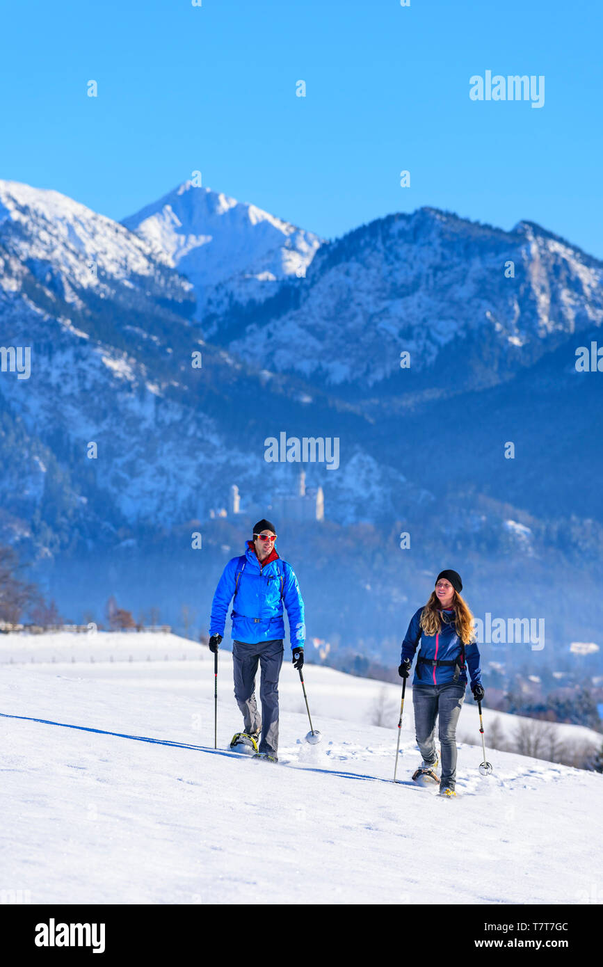 Couple doing a funny tour with snowshoes in wintry nature near Füssen Stock Photo