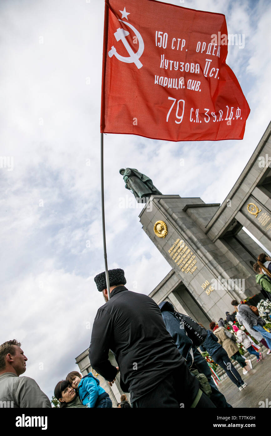 Berlin, Germany. 09th May, 2019. A man holds a flag with hammer and sickle in front of the Soviet Memorial at the Tiergarten on the occasion of the 74th anniversary of Russia's victory in the Second World War. Russia celebrates the end of the war on 9 May, one day later than the West, because in 1945 the German surrender to the Soviet troops took place on the night of 8 to 9 May, at a time when midnight was over in Moscow. Credit: Carsten Koall/dpa/Alamy Live News Stock Photo