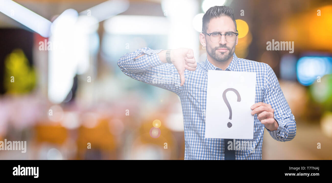 Handsome young business man holding paper with question mark over ...